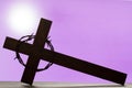 Abstract easter wooden cross and crown of thorns on purple background