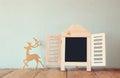 Abstract filtered photo of decorative chalkboard frame and wooden deer over wooden table. ready for text or mockup