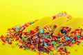 Abstract food background. Durum wheat pasta and colorful candies over yellow background.