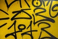 Abstract fragment of creative black scribble on yellow painted concrete wall. Modern background Royalty Free Stock Photo