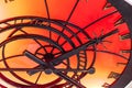 An abstract fragment of a decorative brass clockwork on a shiny red-orange background.