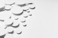 Abstract geometric texture of flying white paper ovals in shining light with soft grey shadows as motion swarm pattern, top view.