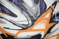 Abstract Graffiti with violet, orange and grey shapes and forms on conrete.