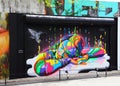 Abstract graffiti painting of a colorful woman resting covering the side of a tall building