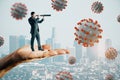 Abstract hand holding businessman with telescope looking into the distant future on daylight city background with virus. Pandemic