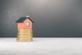 Abstract house on golden coins stack. Light concrete background with mock up place. Mortgage, money and property concept. 3D