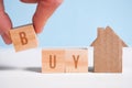 Abstract house made of cardboard hand holds a cube, the word buy. Home purchase concept