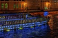 Abstract illuminated ship for travels, excursions with unrecognizable silhouettes of tourists at night in the city