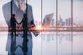 Abstract image of businessman using laptop in modern office interior with panoramic city view, businesspeople shaking hands and