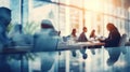 An abstract image depicting a soft and blurred representation of people gathered around a table in an office interior space