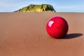 Abstract image of a red perfect shiny sphere on a monotonous sandy surface with a blurred monolithic rock in the background, made Royalty Free Stock Photo