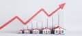 Abstract image of rising house prices on light backdrop with red arrow, chart and houses. Royalty Free Stock Photo