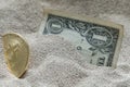 Bitcoin currency seen partially buried in Silicon Sand together with a One Dollar Banknote. Royalty Free Stock Photo