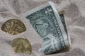 Bitcoin currency seen partially buried in Silicon Sand together with a One Dollar Banknote. Royalty Free Stock Photo