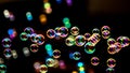 Soap bubbles from the bubble blower in dark or black background. Royalty Free Stock Photo