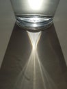 Abstract image of sunlight shining through glass of water, creating a clear ray of light and shadow, hydration theme Royalty Free Stock Photo