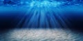 Tropical sand beach on the bottom of underwater dark blue deep ocean wide nature background with rays of sunlight.