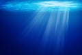 Tropical underwater dark blue deep ocean wide nature background with rays of sunlight.