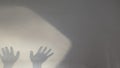 Abstract image of two dark shadows of hands reaching out onto a textured wall, with a bright spotlight effect Royalty Free Stock Photo
