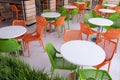 Orange and green chairs around white tables in a food court. Abstract interior in a cafe, airport or family fast food restaurant Royalty Free Stock Photo