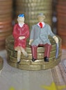 Abstract isolated figures of a retired old couple sitting on a stack of euro coins money - pension and retirement savings concept Royalty Free Stock Photo