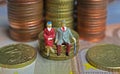 Abstract isolated figures of a retired old couple sitting on a stack of euro coins money - pension and retirement savings concept Royalty Free Stock Photo