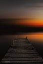Abstract lake landscape at sunset with an old wooden boardwalk. Dock in lake with abstract blurred background in dark sunset