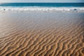 Abstract landscape of wind-carved sandy ripples against a blurred ocean background.. AI generated. Royalty Free Stock Photo