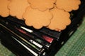 Cookies in the shape of flowers lie on a stack of black books on a green tablecloth.