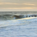 Abstract long exposure landscape image of waves crashing onto groynes on beach during sunset