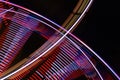 Abstract long exposure of a spinning Ferris wheel and a fast ride on a fun fair at night, colorful light traces in motion blur Royalty Free Stock Photo