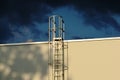 Aluminum roof access ladder detail with safety cage. dramatic dark blue sky Royalty Free Stock Photo