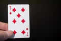 Abstract: man hand holding playing card seven of Diamonds on a black background with copyspace Royalty Free Stock Photo