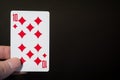 Abstract: man hand holding playing card Ten of Diamonds isolated on black background with copyspace Royalty Free Stock Photo