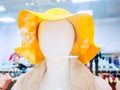 Abstract mannequin head in yellow hat on blurred shop background