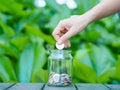 Abstract money saving women hand put coin to glass jar