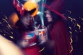 Abstract motion blur of two young woman in witch halloween costumes for Halloween party with glasses of cocktails. Halloween party