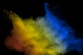 Abstract multicolored powder explosion on black background.Red yellow blue dust particles splatter on background Royalty Free Stock Photo