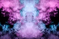 Abstract mystical bat silhouette straightened wings and head from streams of colorful smoke evaporating from a vape illuminated by Royalty Free Stock Photo