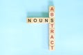 Abstract nouns concept in English grammar noun education. Wooden block crossword puzzle flat lay in blue background.