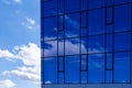 Abstract office building background. Clouds and sky reflected in windows of modern office building. Skyscraper in the city Royalty Free Stock Photo