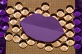 abstract orange background with dots and purple paper lips as copy space and beads that reflect colors differently