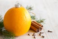 Abstract orange christmas ball, with cinnamon, cloves and christmas tree in background
