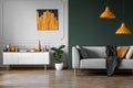 Abstract orange painting on grey wall of stylish living room interior with white wooden furniture and grey couch Royalty Free Stock Photo