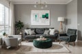 Abstract painting on grey wall o contemporary living room interior with emerald green armchair with round pillow, commode and couc Royalty Free Stock Photo