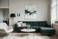 Abstract painting on grey wall o contemporary living room interior with emerald green armchair with round pillow, commode and couc Royalty Free Stock Photo