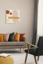 Abstract painting on grey wall of retro living room interior with beige sofa with pillows, vintage dark green armchair and yellow Royalty Free Stock Photo