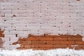 Abstract pattern with brown brick wall partially covered with snow
