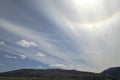 A blue sky, with ribbon-like clouds and the solar corona