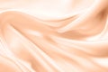 Abstract peach silk fabric texture background. Peach Fuzz color of the year 2024. Elegant luxury satin cloth with wave